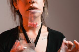 Woman in Black Blazer Holding Clear Plastic Pack with pills