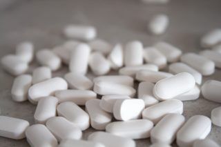 white medication pills on brown surface