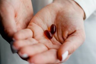 Hand holding two brown pills