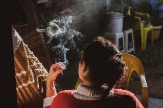 photo of a woman from the back holding a lit cigarrette