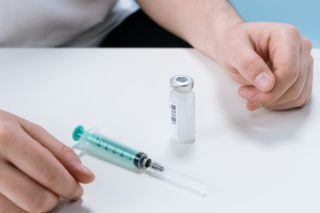 A Syringe and a Vial on a White Surface